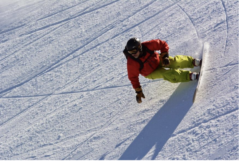 snowboarder carving a steep slope on heelside edge