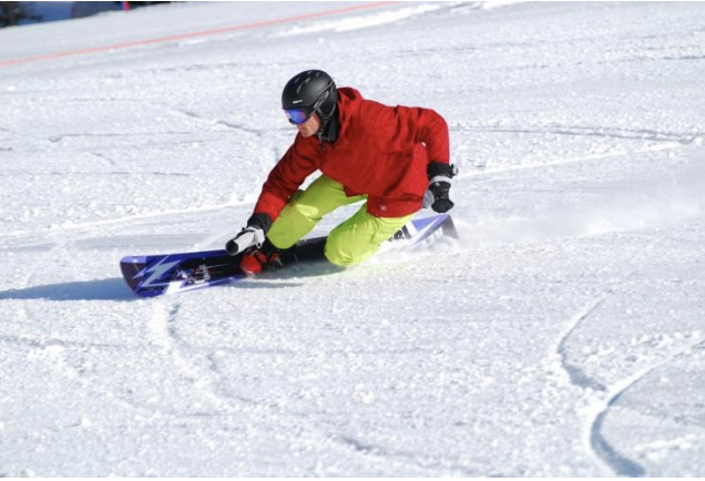 Snowboarder on toeside edge with both knees visible